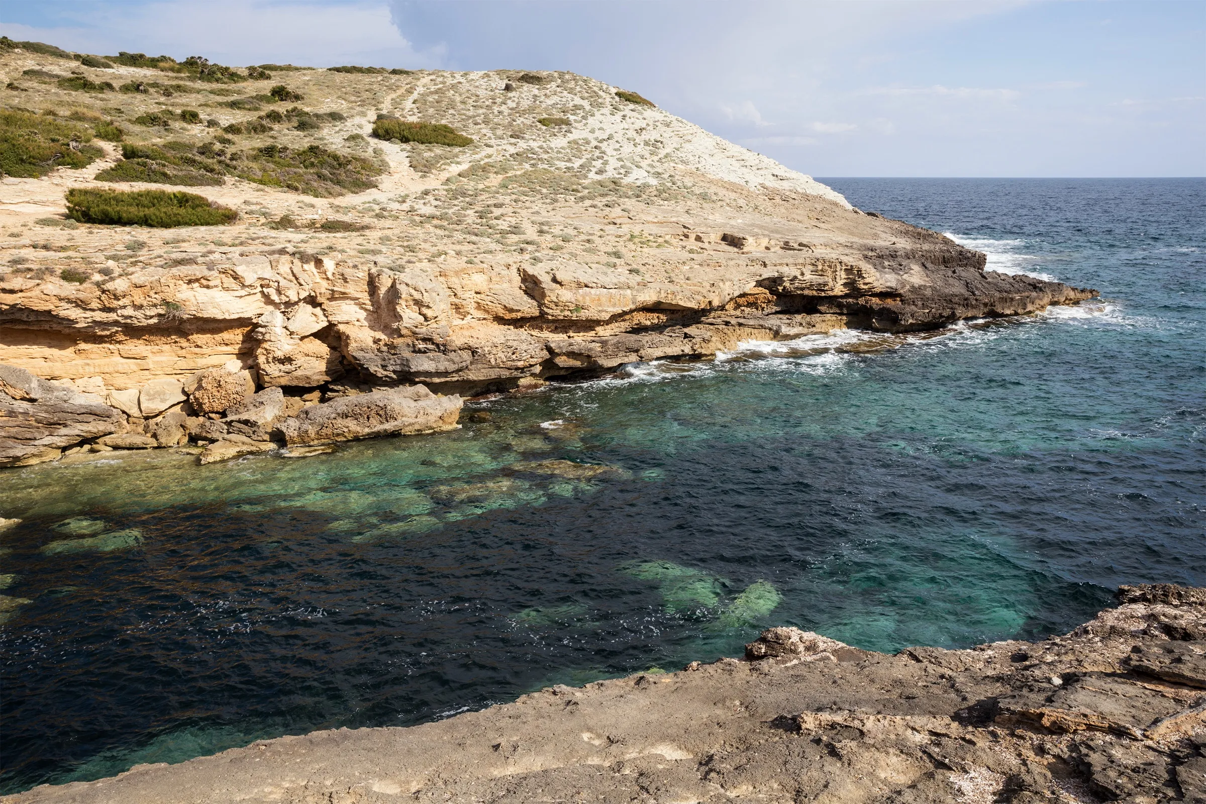 El entrante de Cala Estreta, con el agua verde y clara entre paredes de roca caliza y la punta que se abre al mar