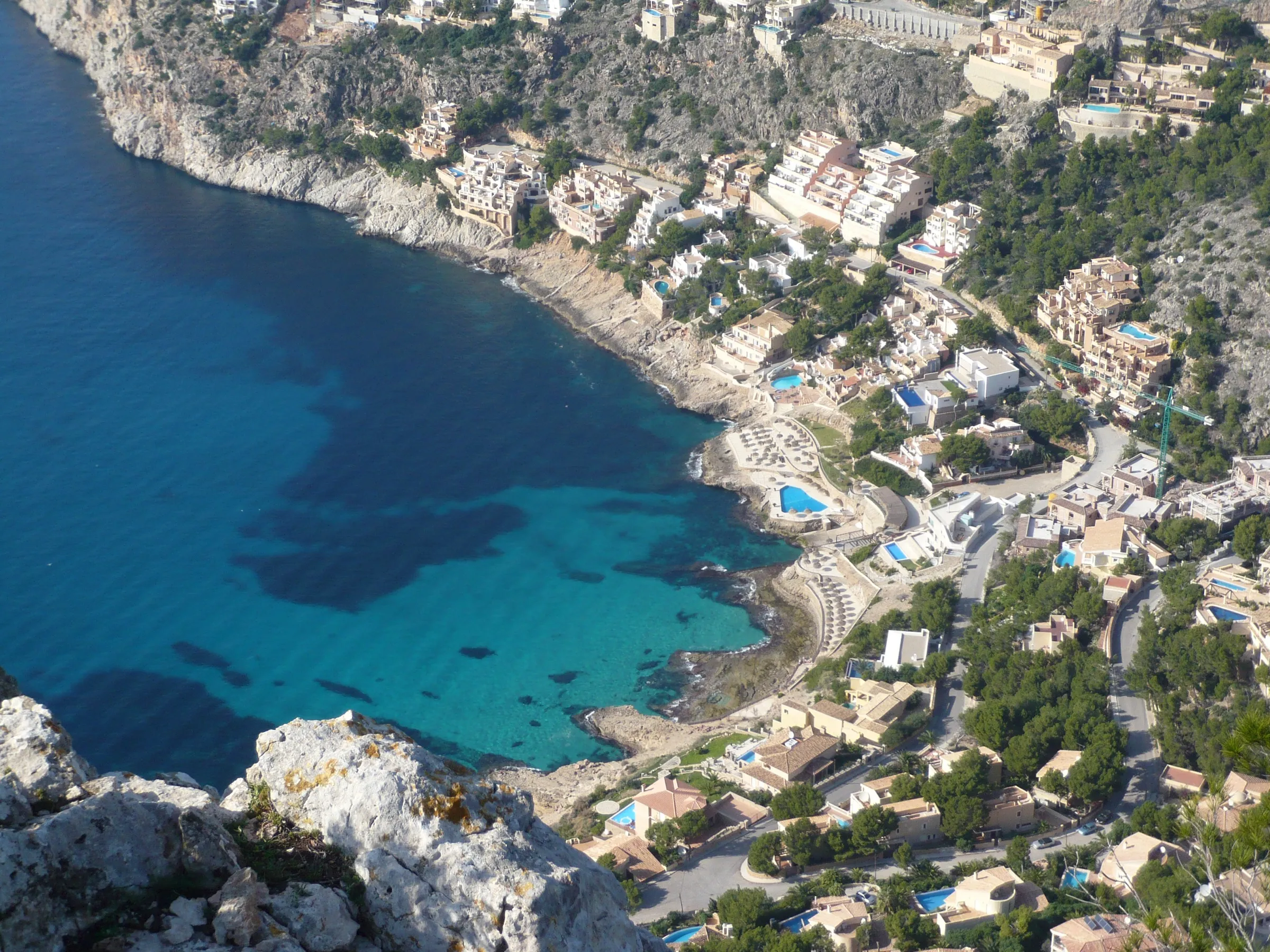 Cala Llamp desde lo alto de sa Talaia, con el agua turquesa al fondo de la cala y las casas en la ladera