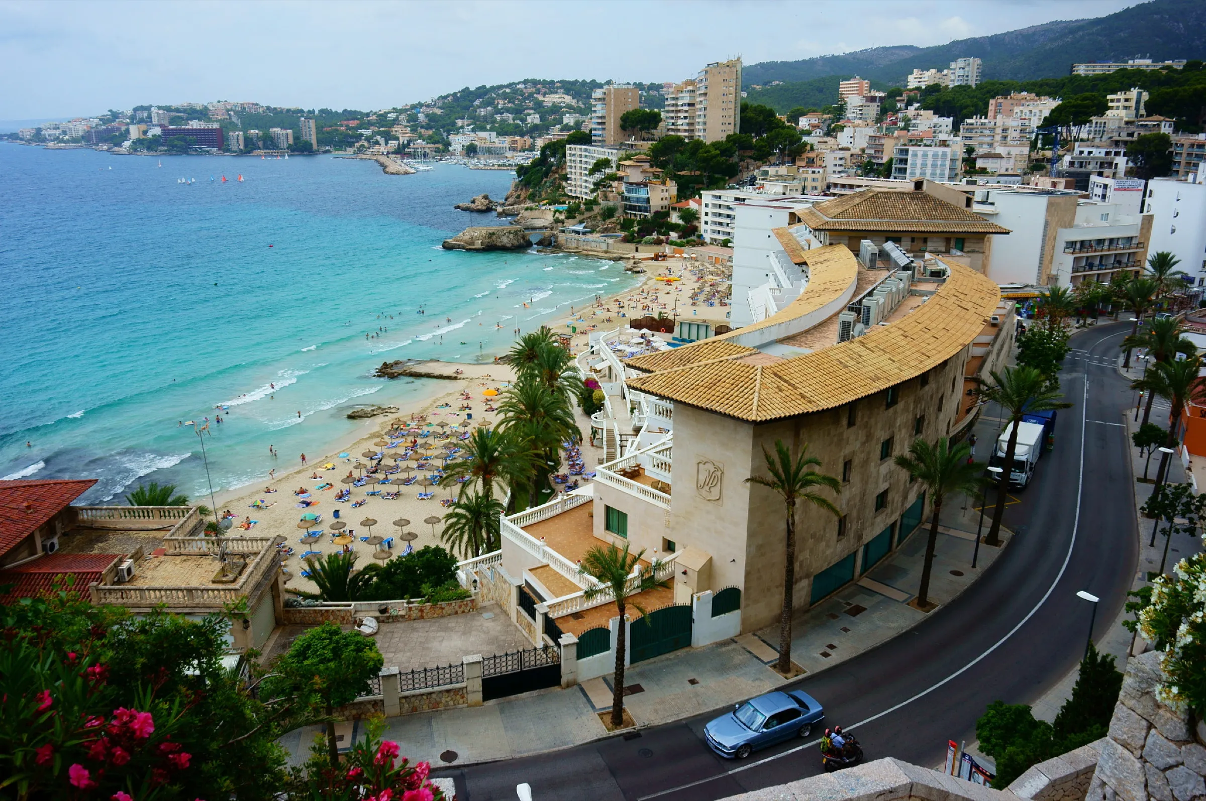 Cala Major beach from above, with turquoise water, sand full of parasols and the buildings of the district