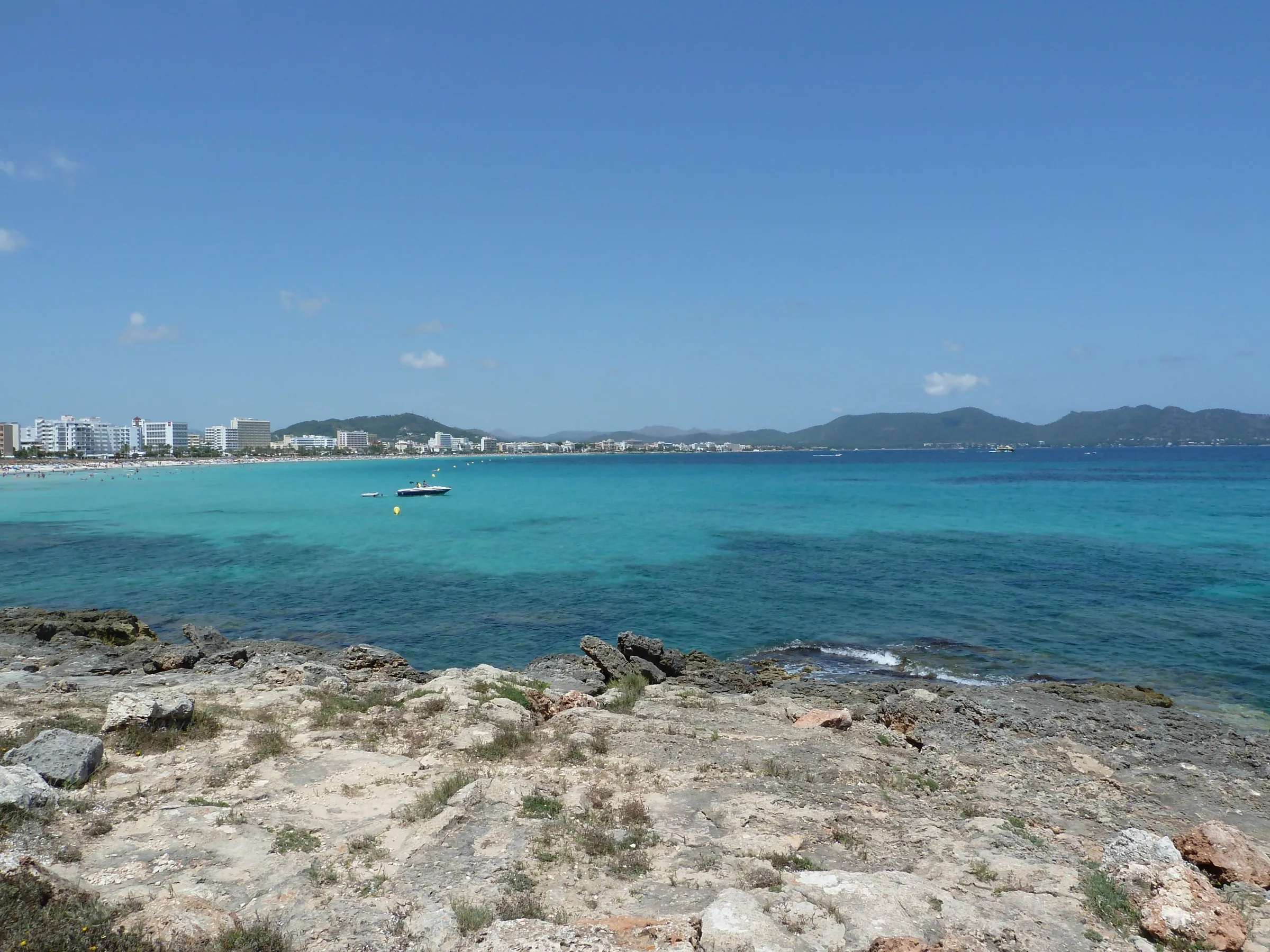 The bay of Cala Millor seen from the rocky coast, with turquoise water and the hotels in the background