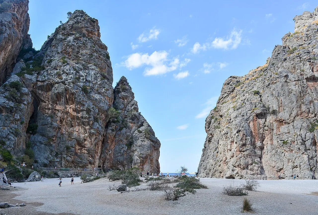 El lecho de grava del Torrent de Pareis junto a su desembocadura, con matorral y grandes farallones de roca
