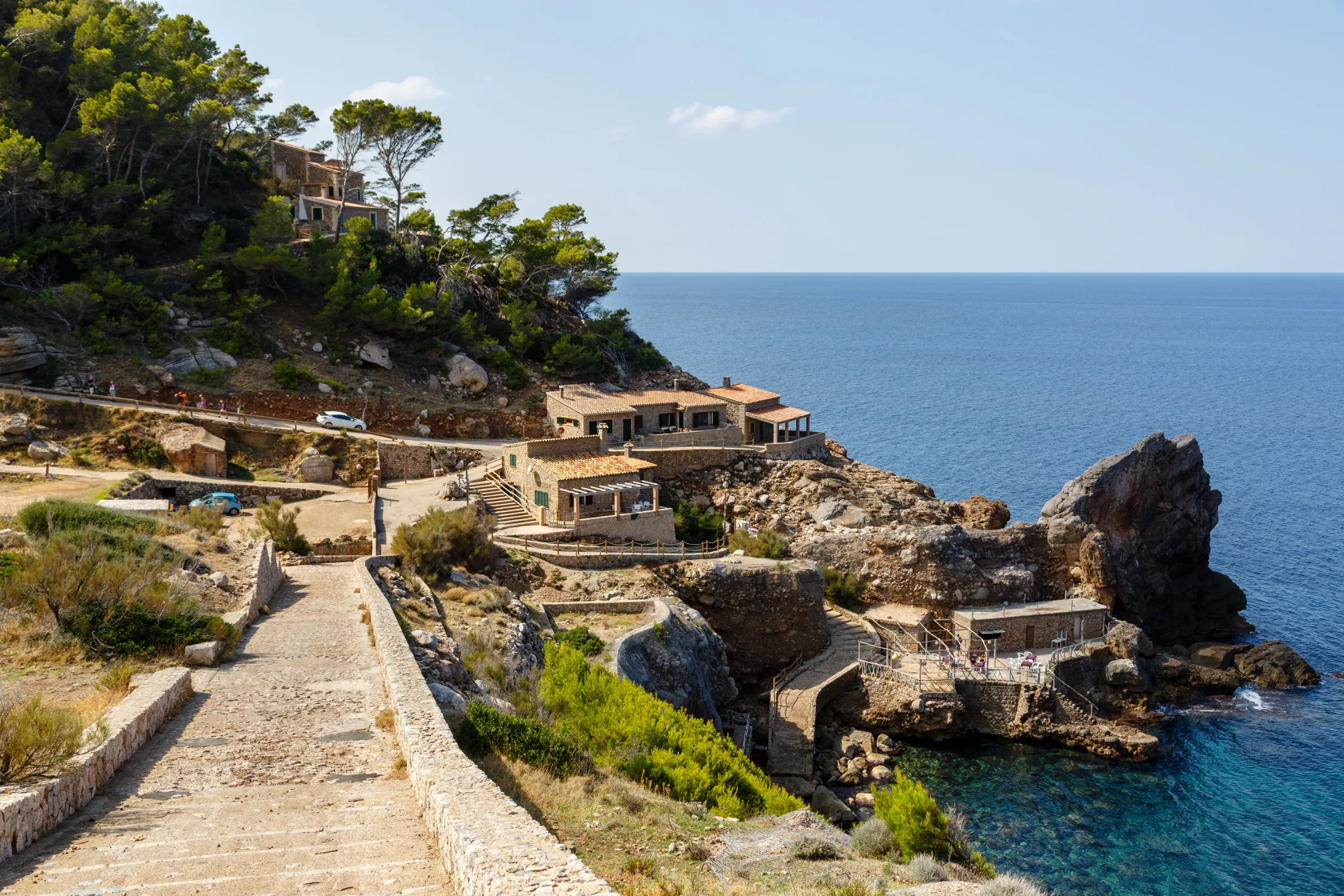 El último tramo de la carretera que baja a Cala d'Estellencs, con las casas sobre la roca y el mar abierto al fondo