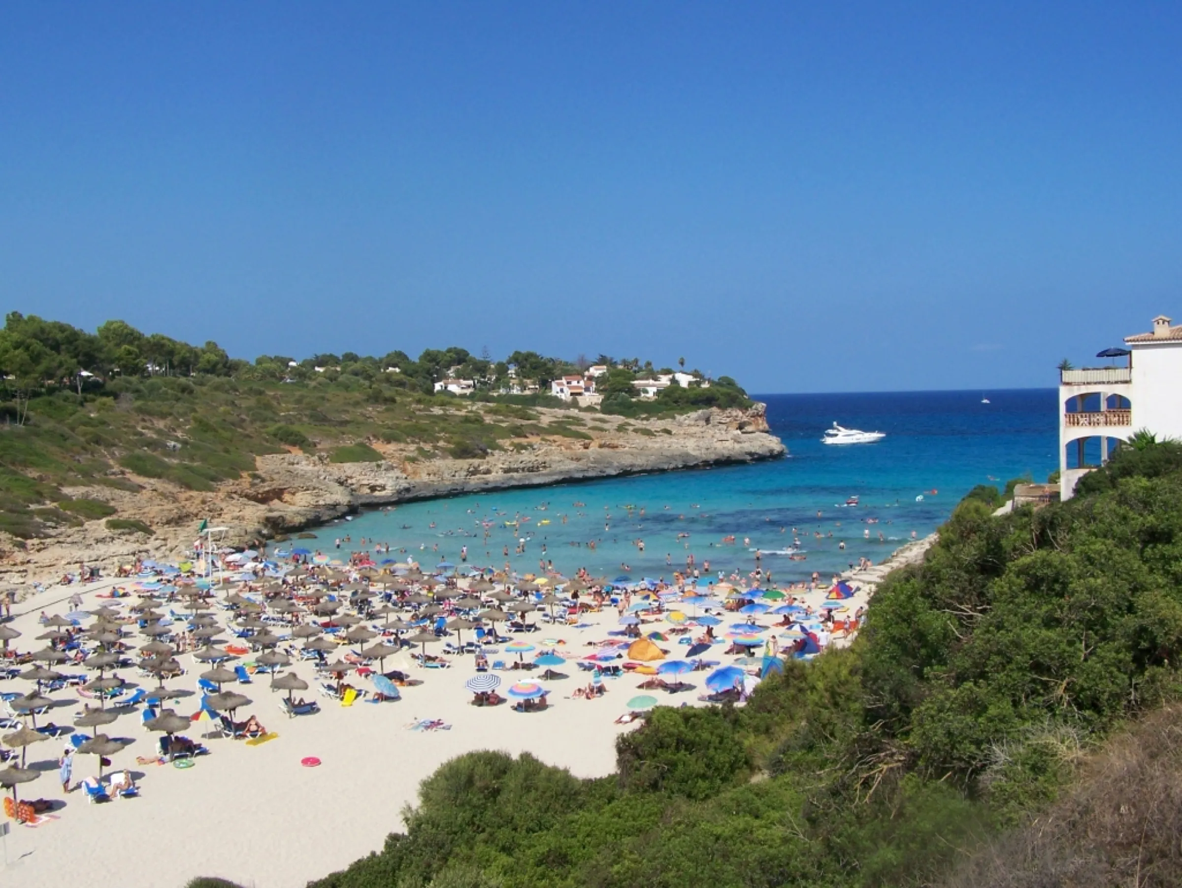 La playa de Cala Mendia con sombrillas de paja y el entrante de agua turquesa que se abre hacia el mar