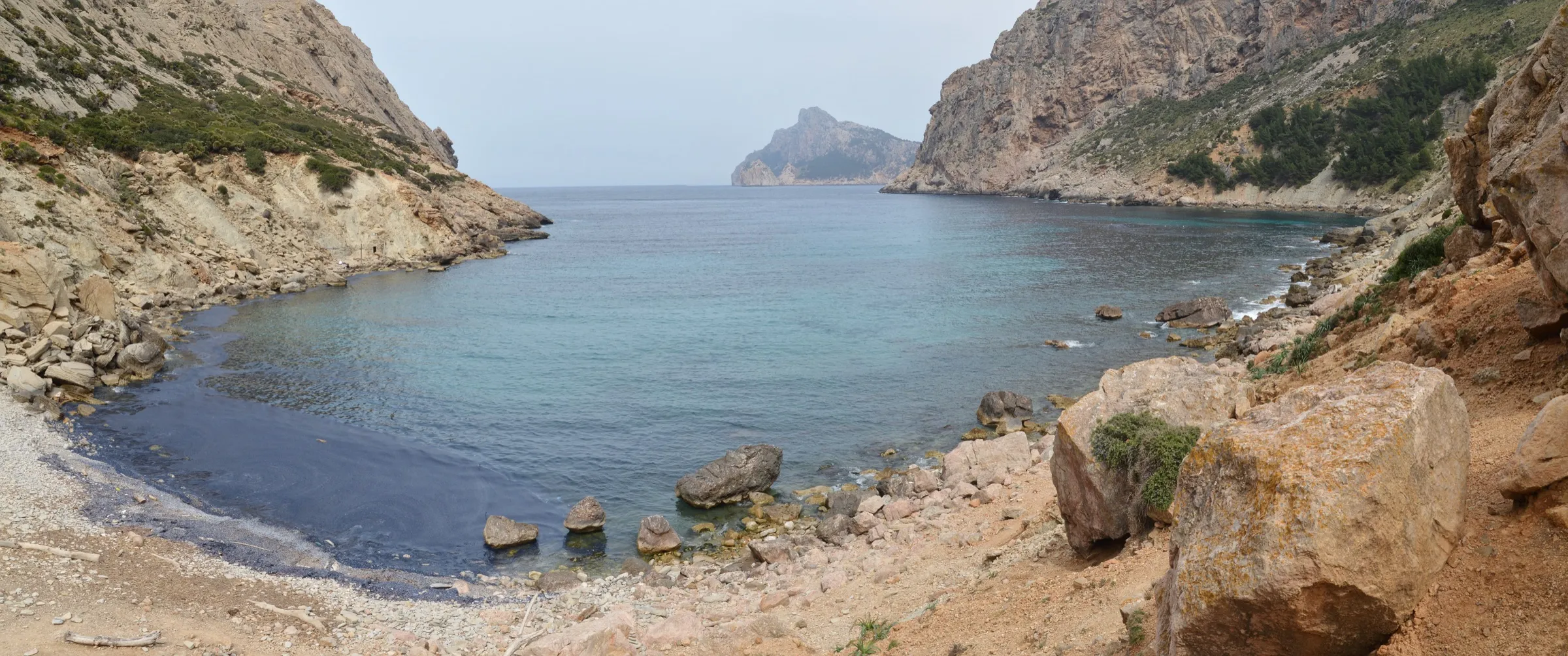 Panorámica de Cala Bóquer con la playa de cantos, los acantilados a los lados y el islote des Colomer en la boca