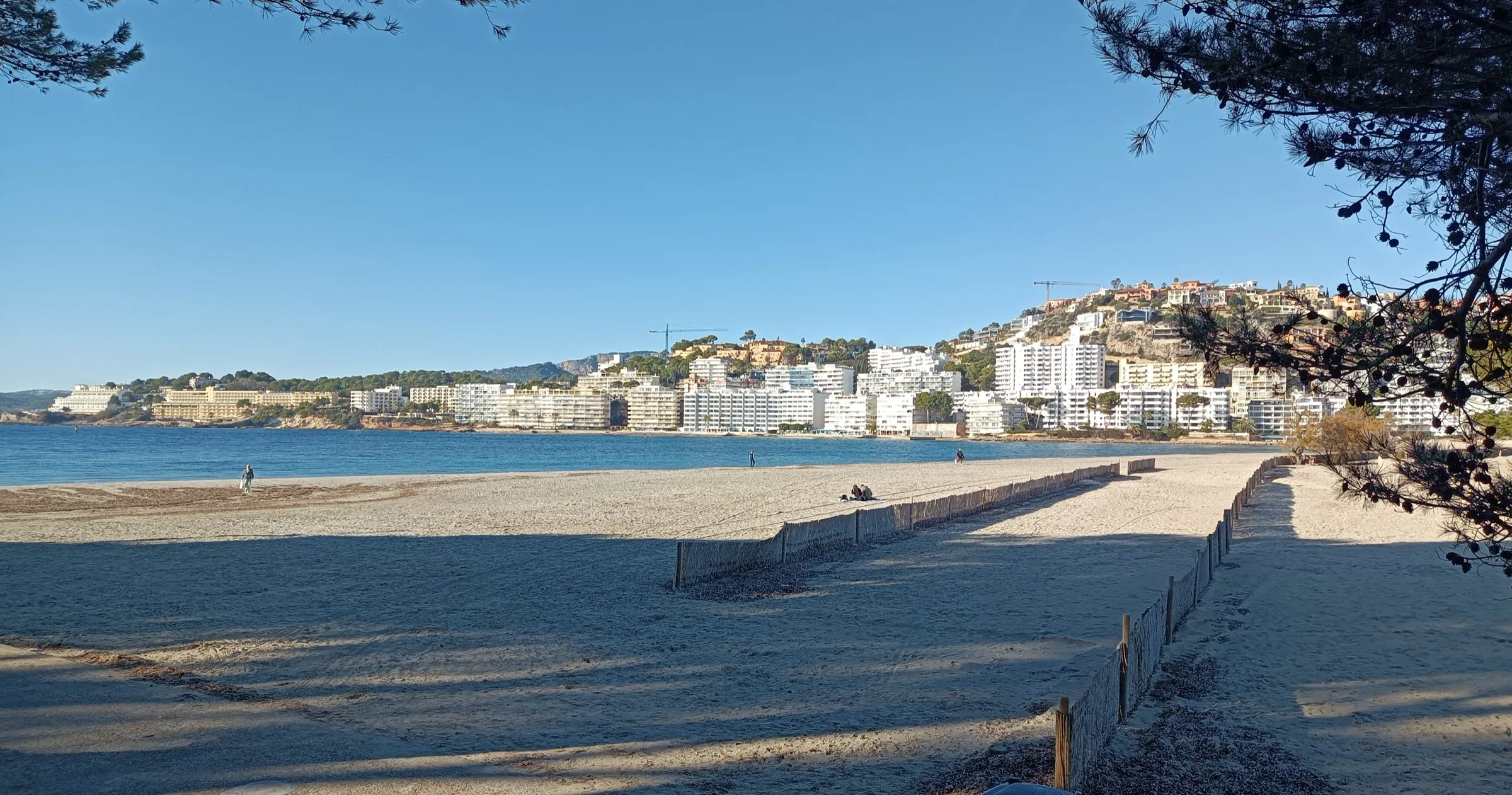 Der breite Sand des Strands von Santa Ponça mit dem Ort entlang der Bucht