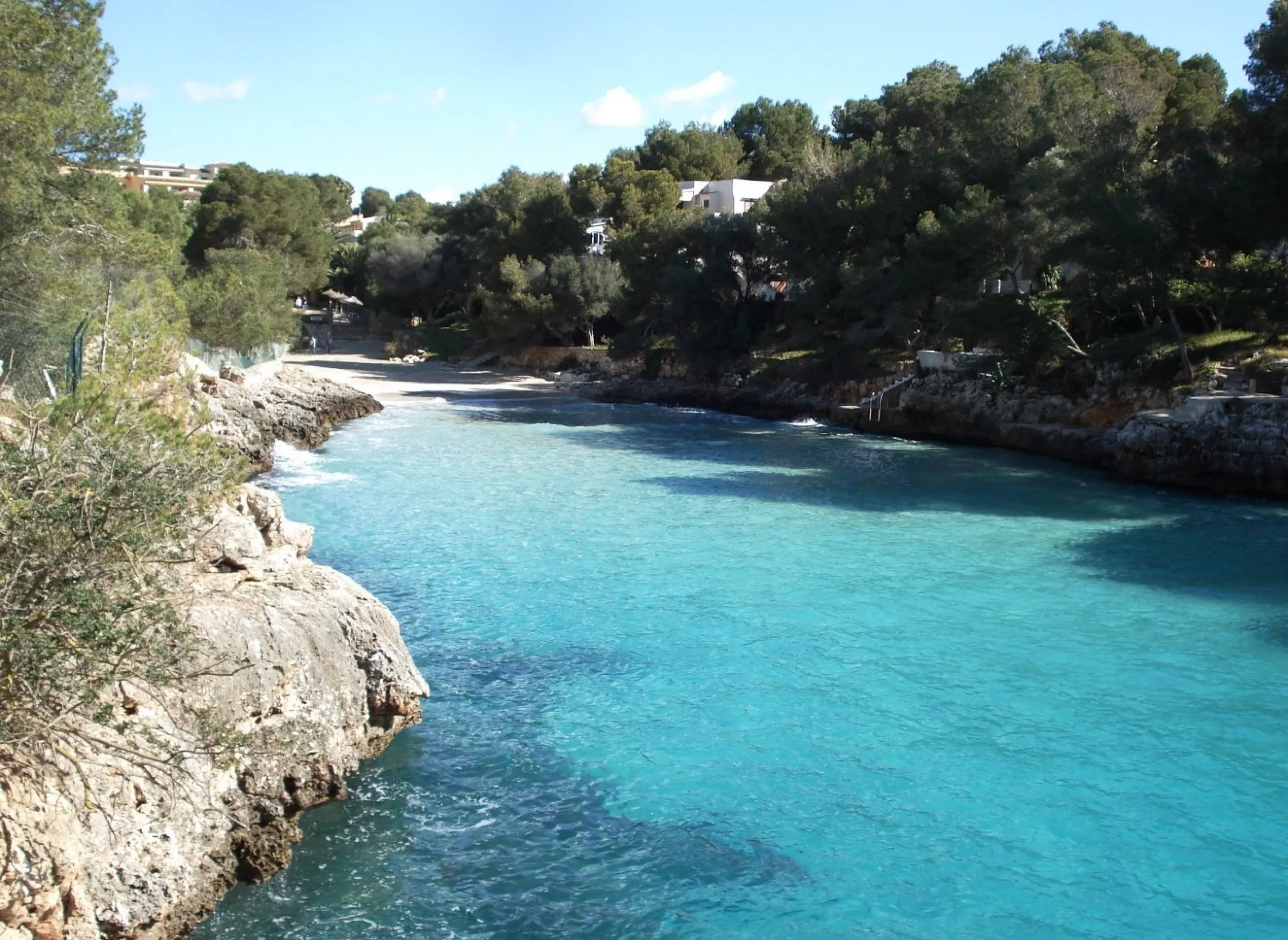 Klares türkises Wasser in der Cala Serena, mit dem Sand dahinter und dem felsigen Ufer