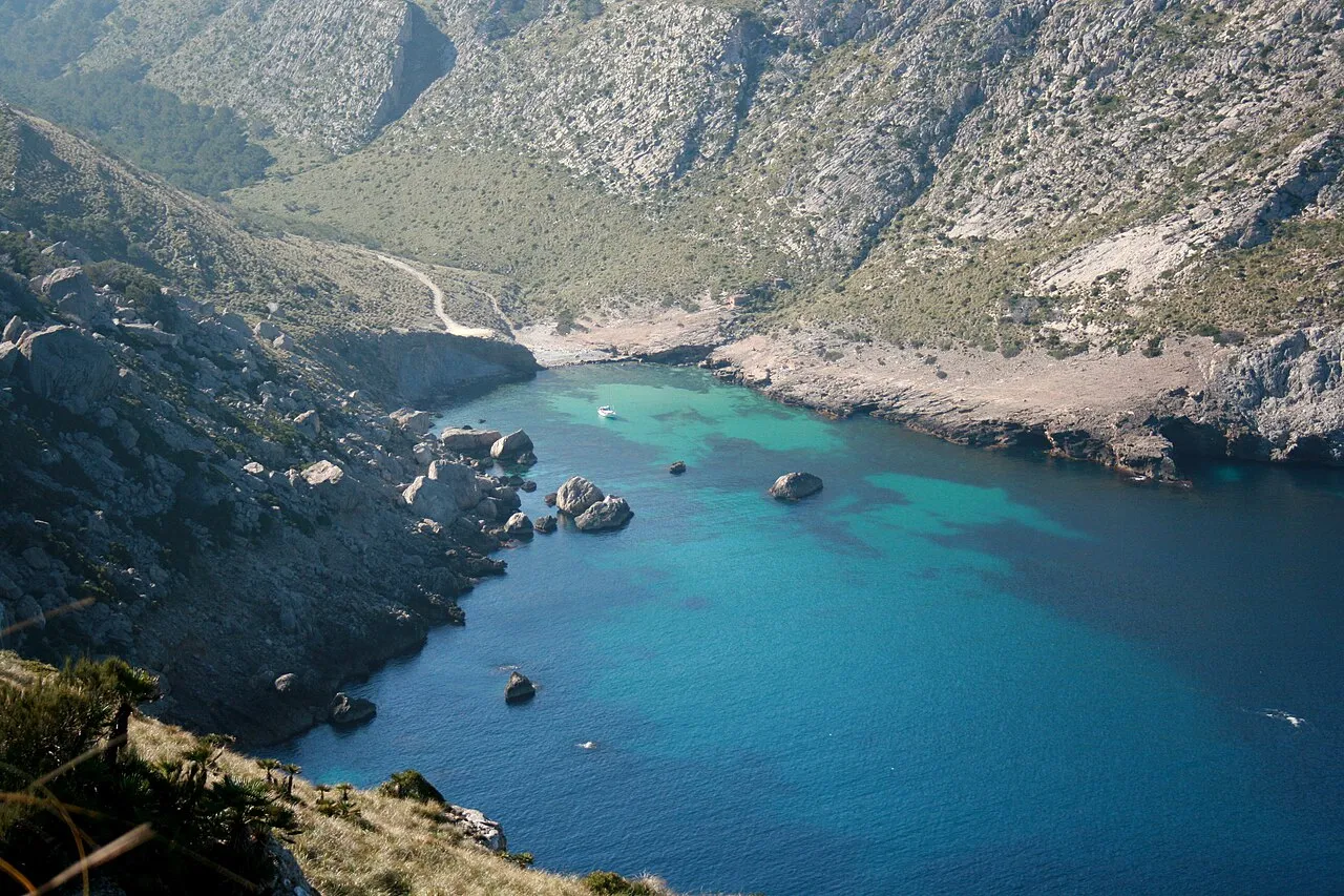Cala Figuera vista desde la carretera de Formentor, con la playa al fondo y el camino de tierra que baja por el valle