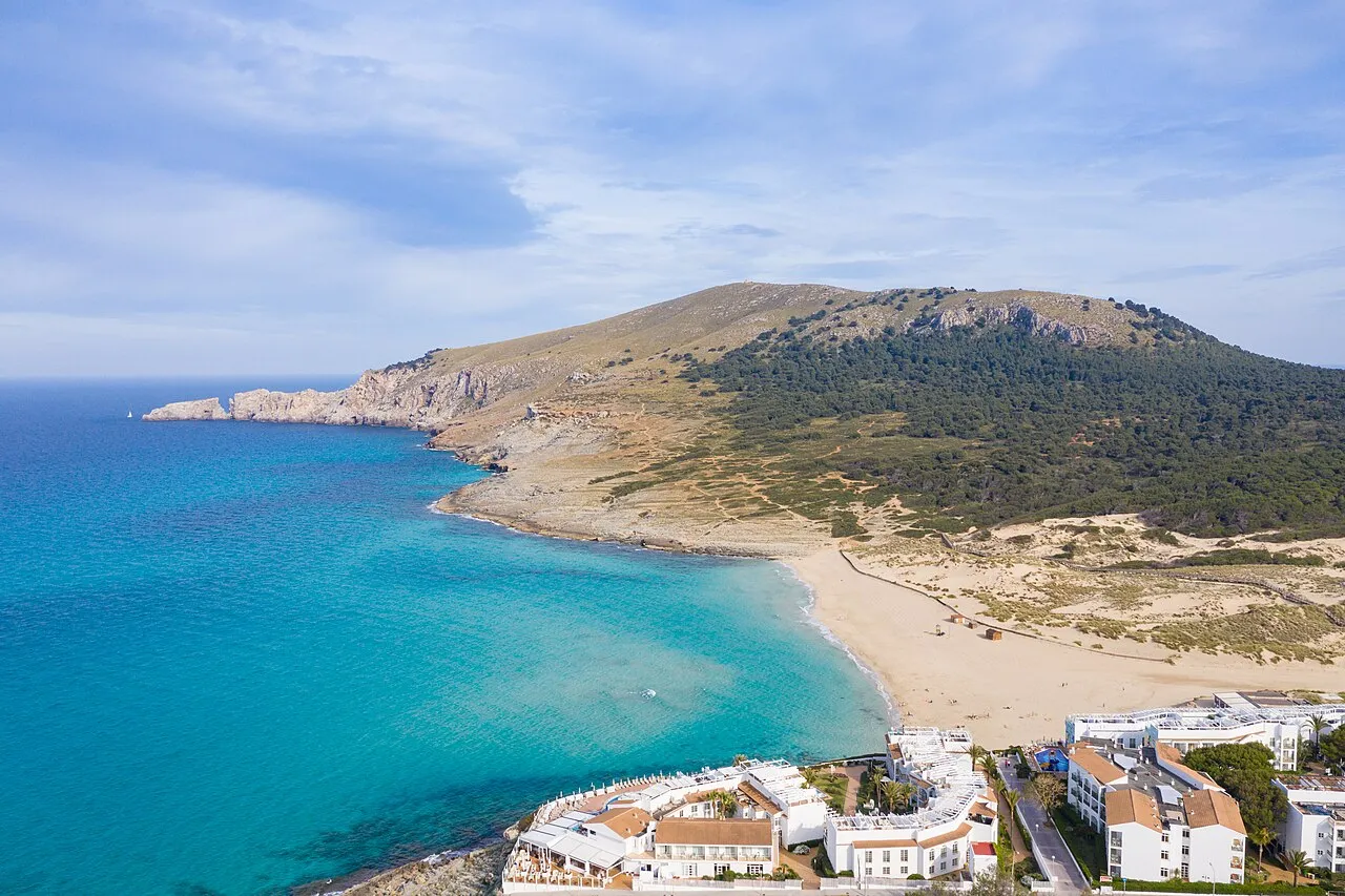 Vista aérea de la bahía de Cala Mesquida, con los hoteles en primer plano y el monte y las dunas al otro lado