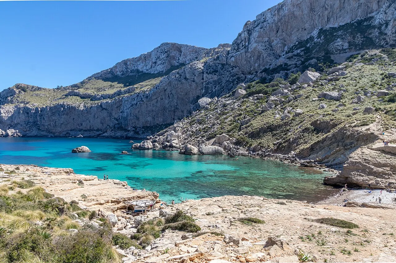El fondo de Cala Figuera desde las rocas planas de la orilla, con las paredes de caliza detrás
