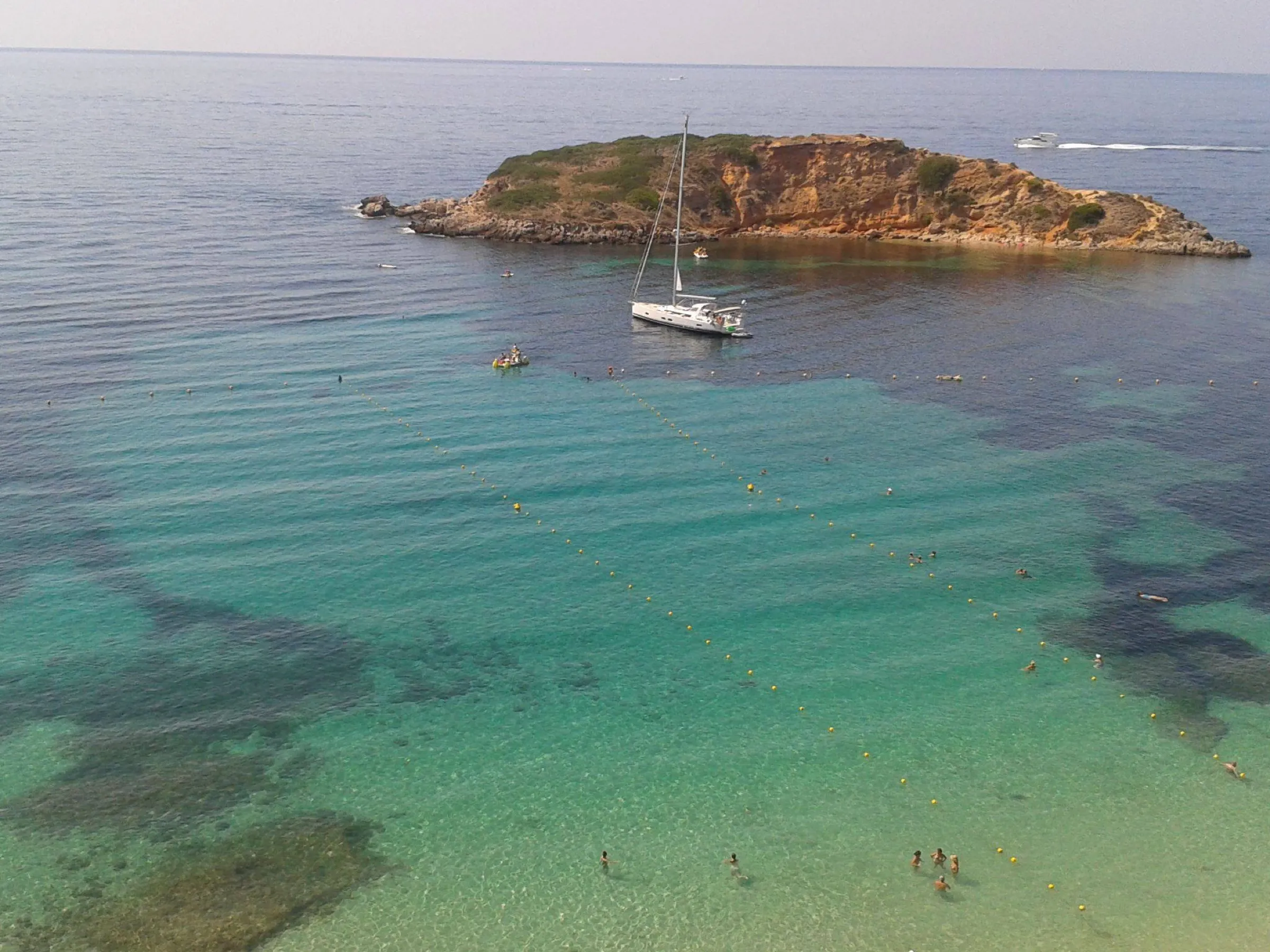 Un velero fondeado sobre fondo de arena y posidonia frente a la Illa d'en Sales