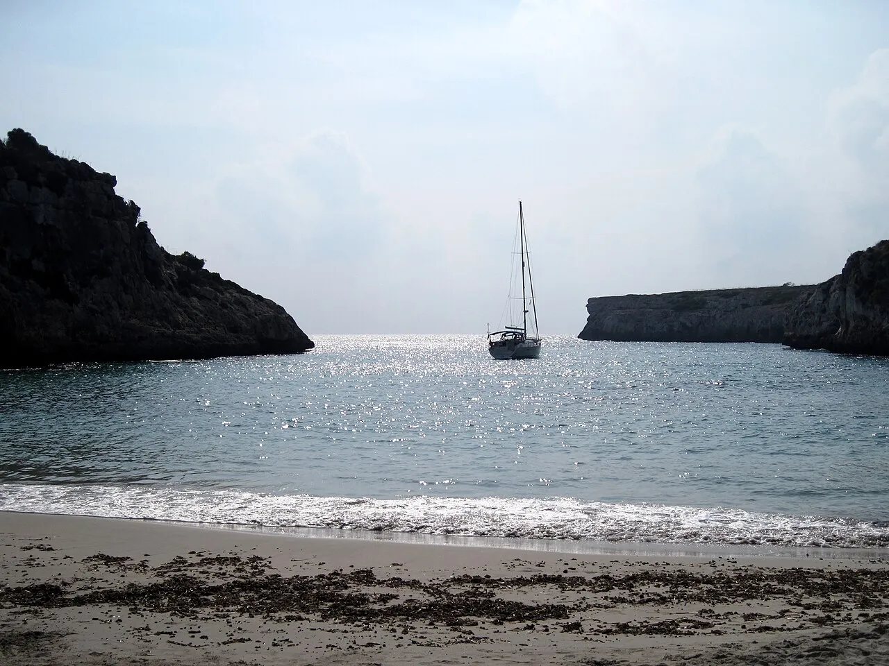 Velero fondeado en la boca de Cala Magraner, visto desde la orilla
