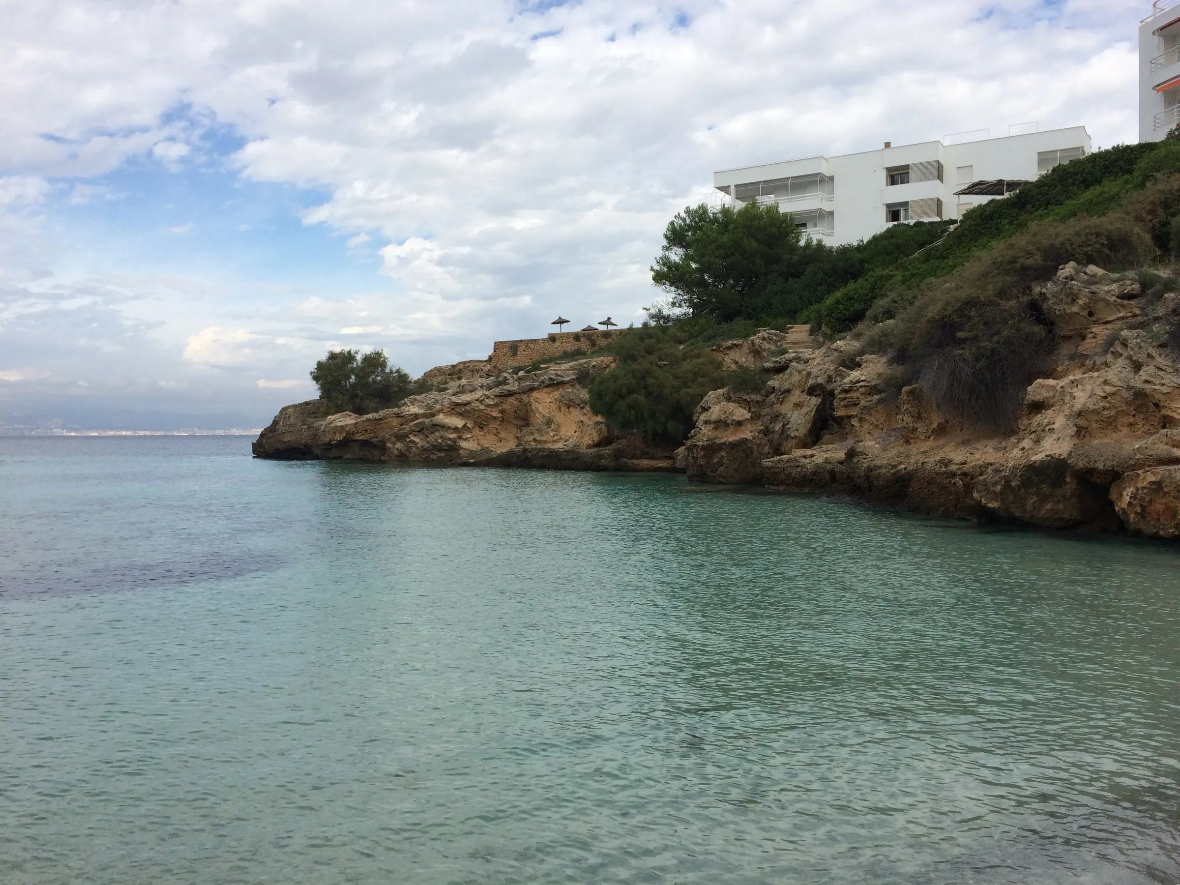 Ruhiges Wasser der Cala Blava an der Felsspitze auf einer Seite der Bucht