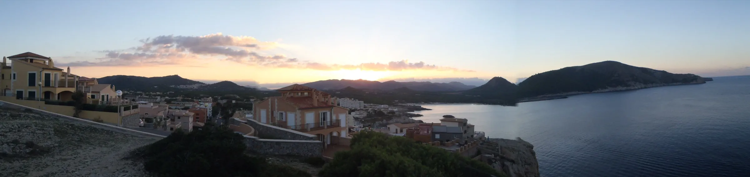 Sonnenuntergang an der Cala Lliteres, mit den Häusern von Cala Rajada und der Küste Richtung Cala Agulla