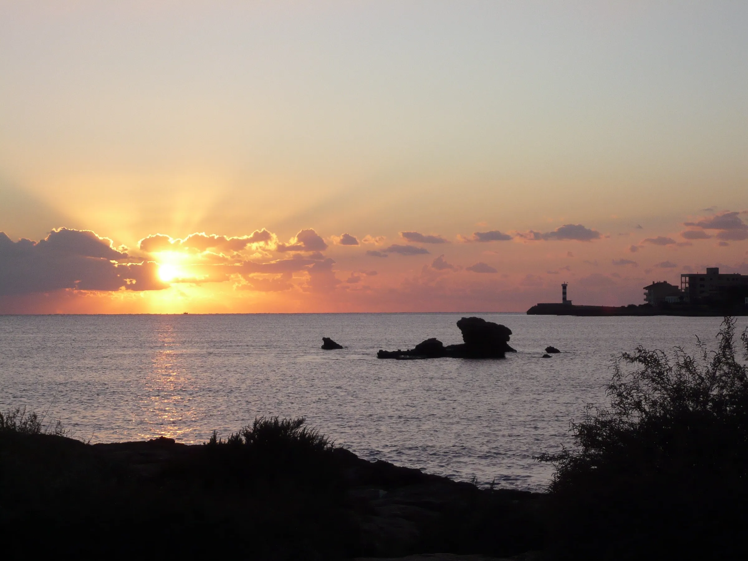 Sunset over the sea from es Dolç, with the Colònia harbour lighthouse on the right