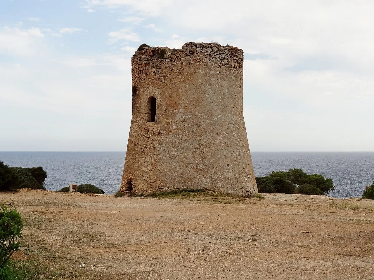 Torre de vigía de Cala Pi, de piedra y planta circular, con el mar detrás