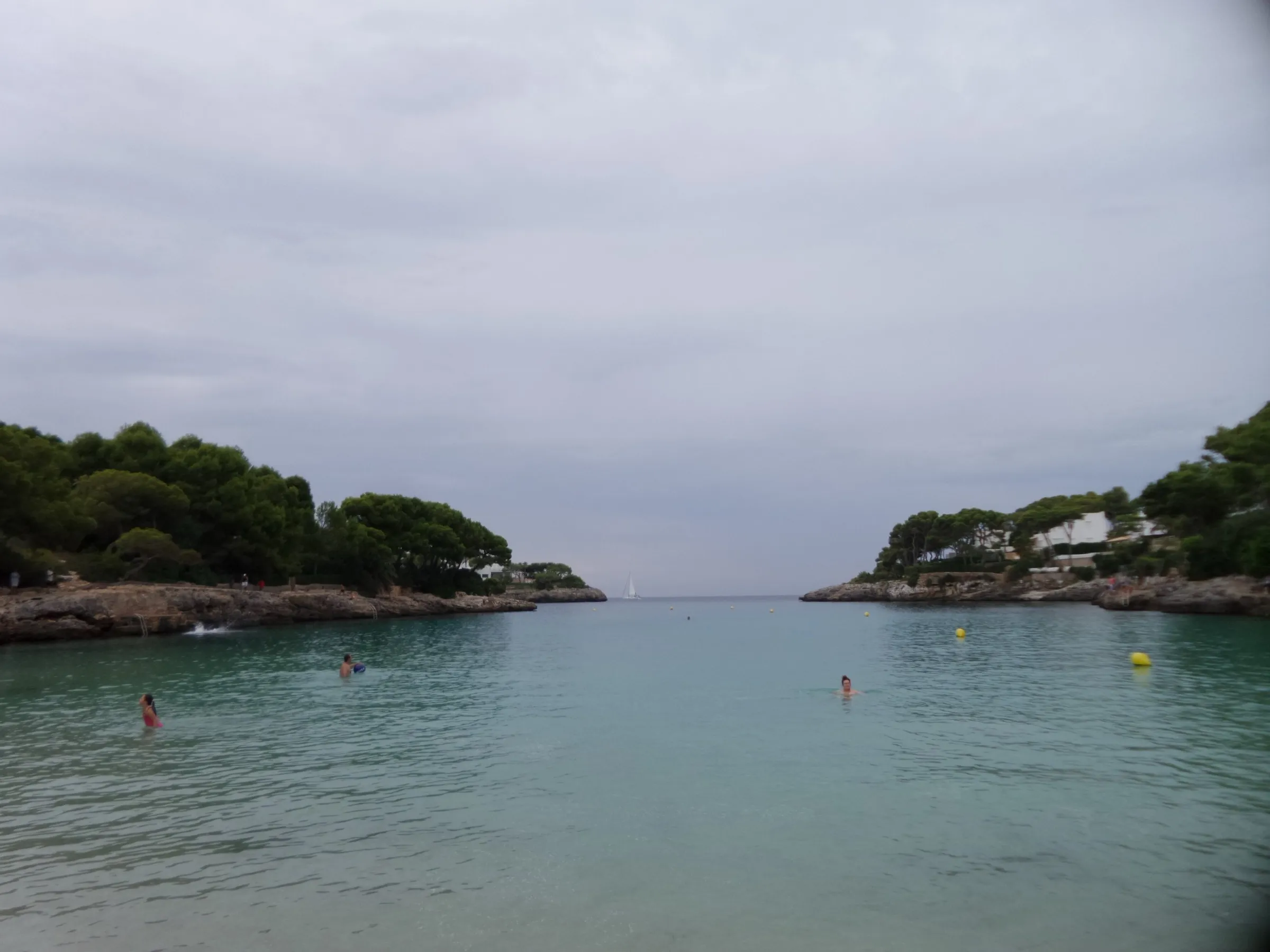 View from the water towards the mouth of Cala Gran, between two rocky points with pines