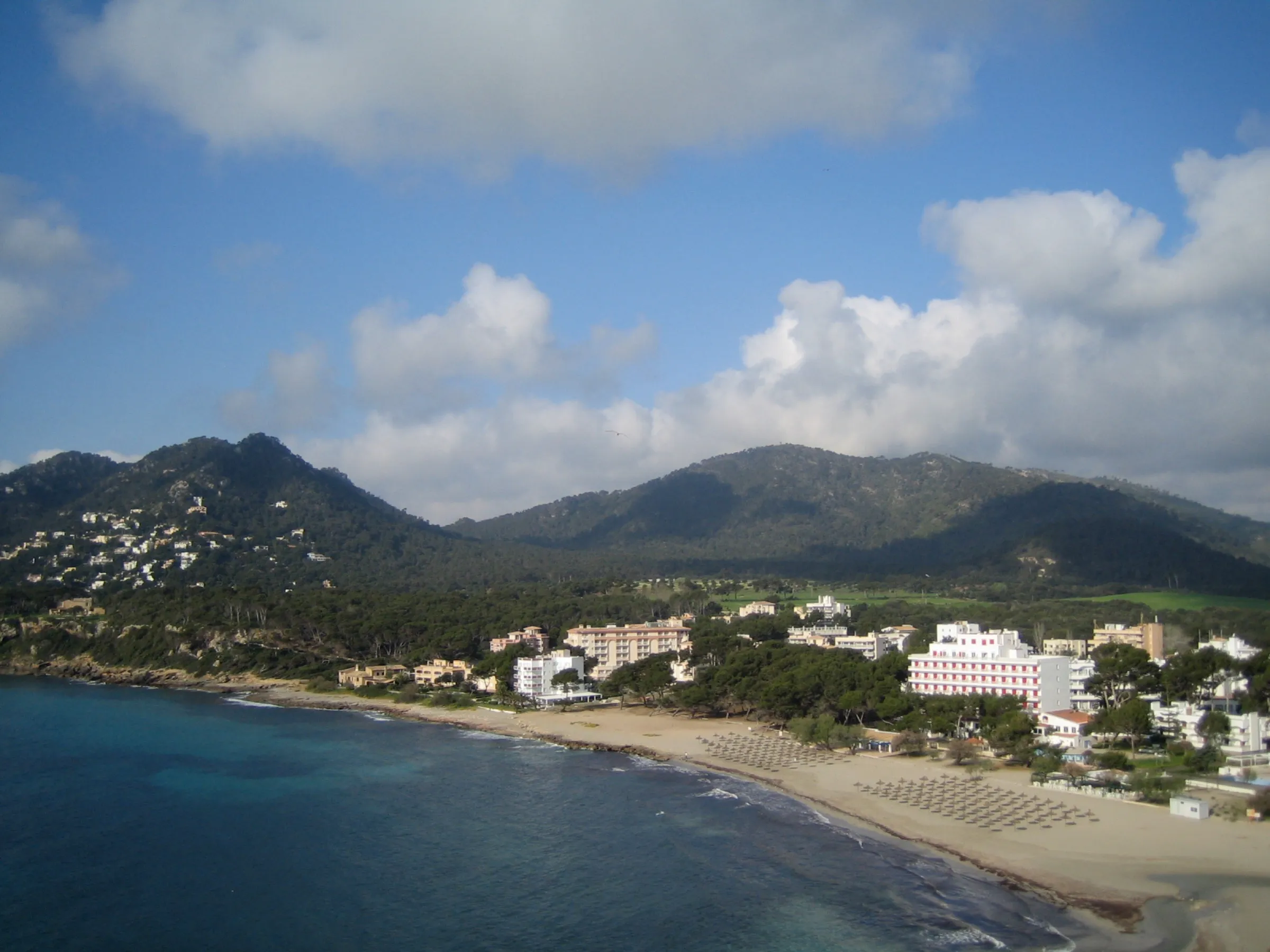 The bay of Canyamel from above, with the beach, the hotels and the mountains behind