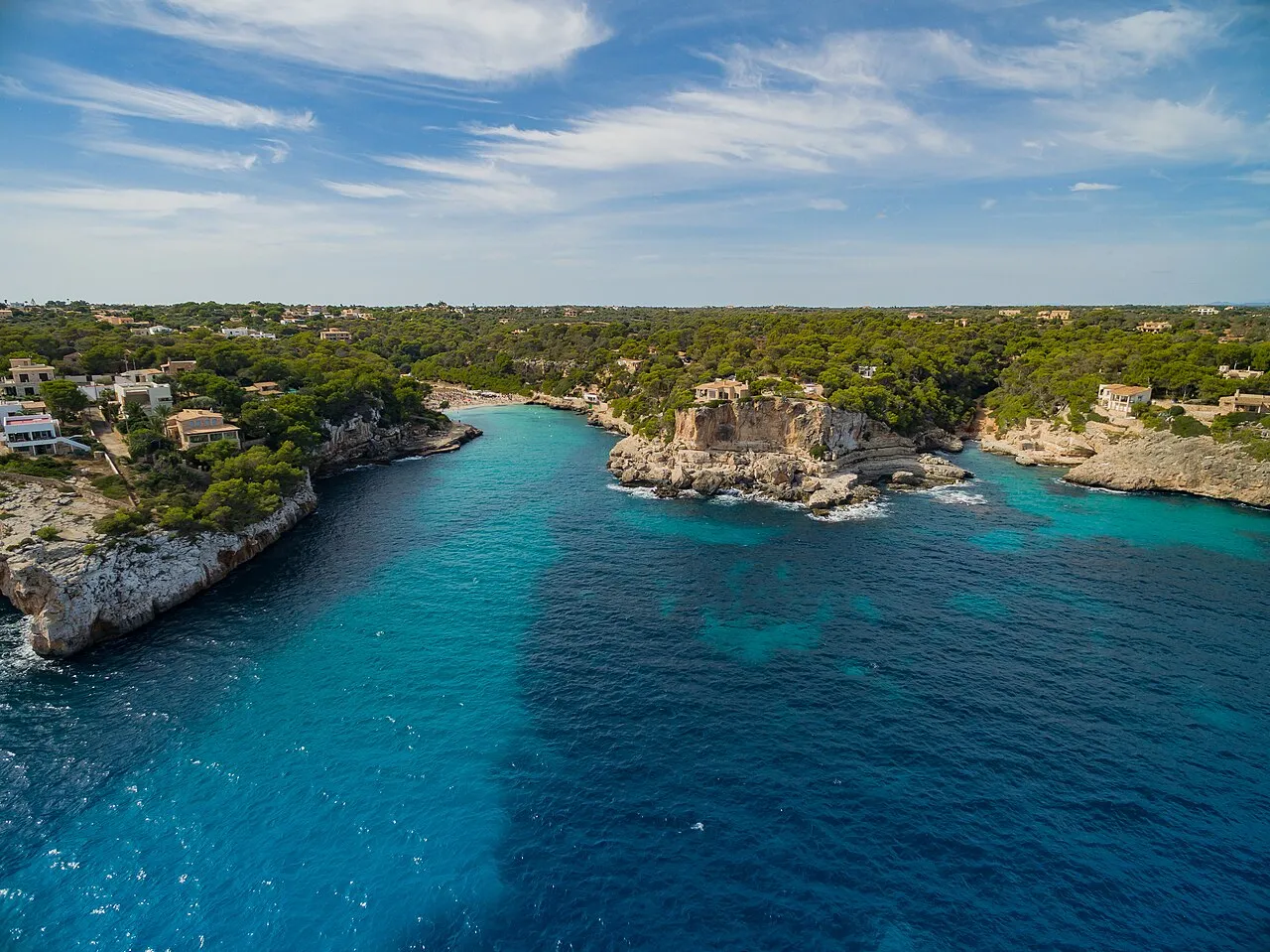 Vista aérea desde el mar de la bahía de Cala Llombards, con la costa rocosa y el pinar alrededor