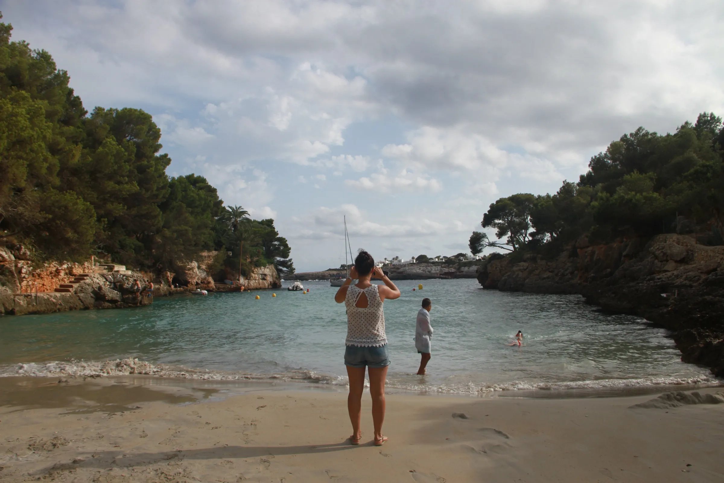 View from the shore of Cala Serena towards the mouth of the inlet, between two rock walls with pines