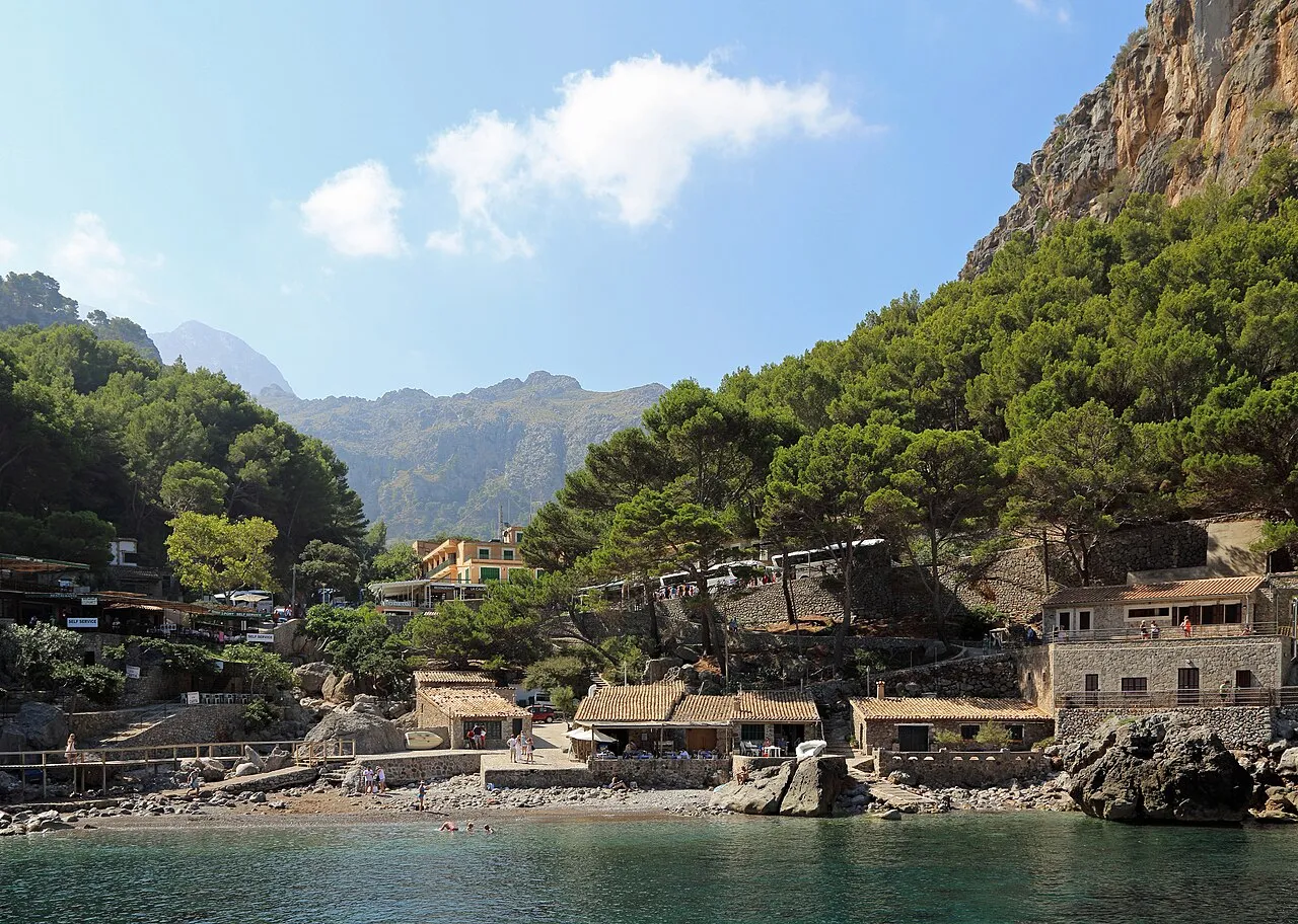 Sa Calobra desde el mar, con las casas de piedra junto a la orilla, el pinar y las montañas de la Tramuntana detrás
