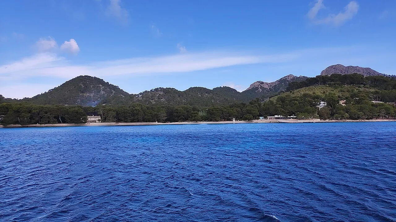 La playa de Formentor vista desde el mar, una línea de arena al pie del pinar y de las montañas