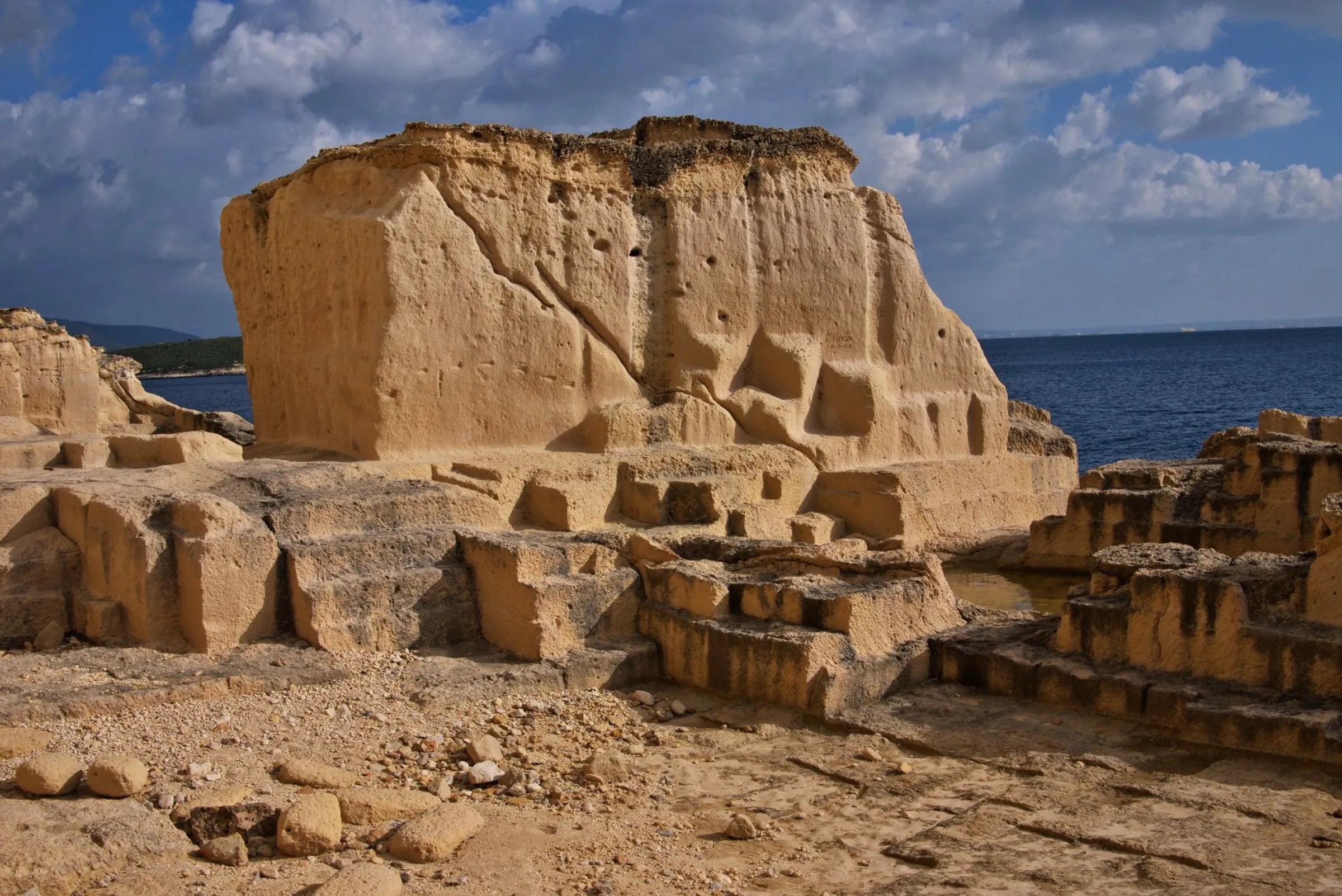 Antigua cantera de marès junto a Cala Vinyes, con bloques cortados en la roca y el mar detrás