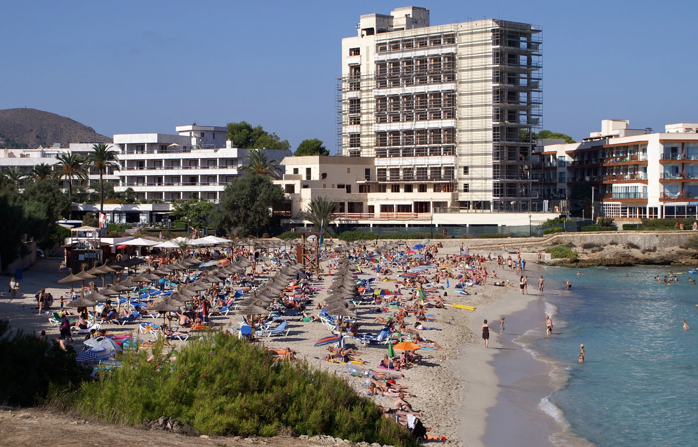 Son Moll en temporada alta, con la arena cubierta de sombrillas y hamacas delante de los hoteles