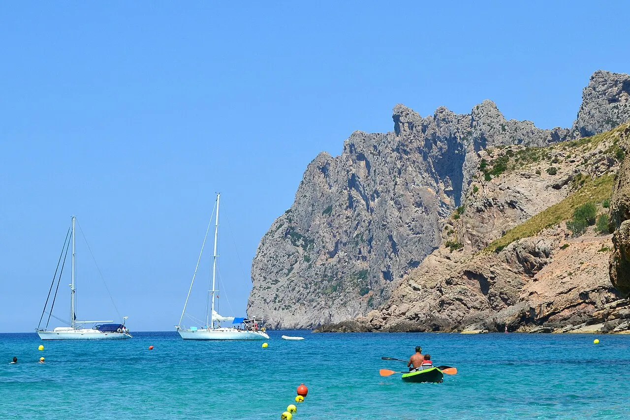Veleros fondeados y un kayak en la bahía, bajo las paredes de roca del Cavall Bernat