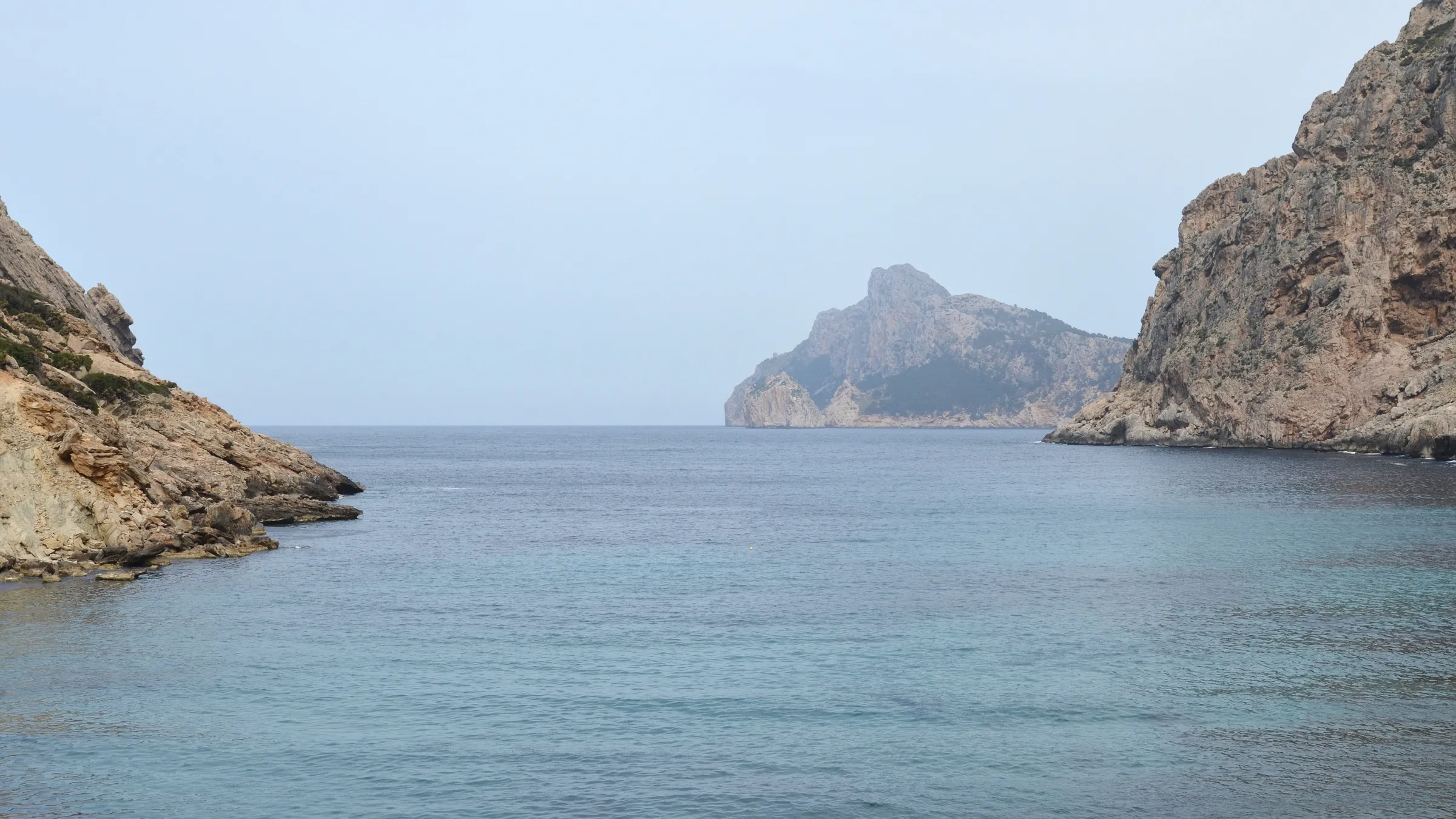 La boca de Cala Bóquer entre dos acantilados, con el islote des Colomer al fondo